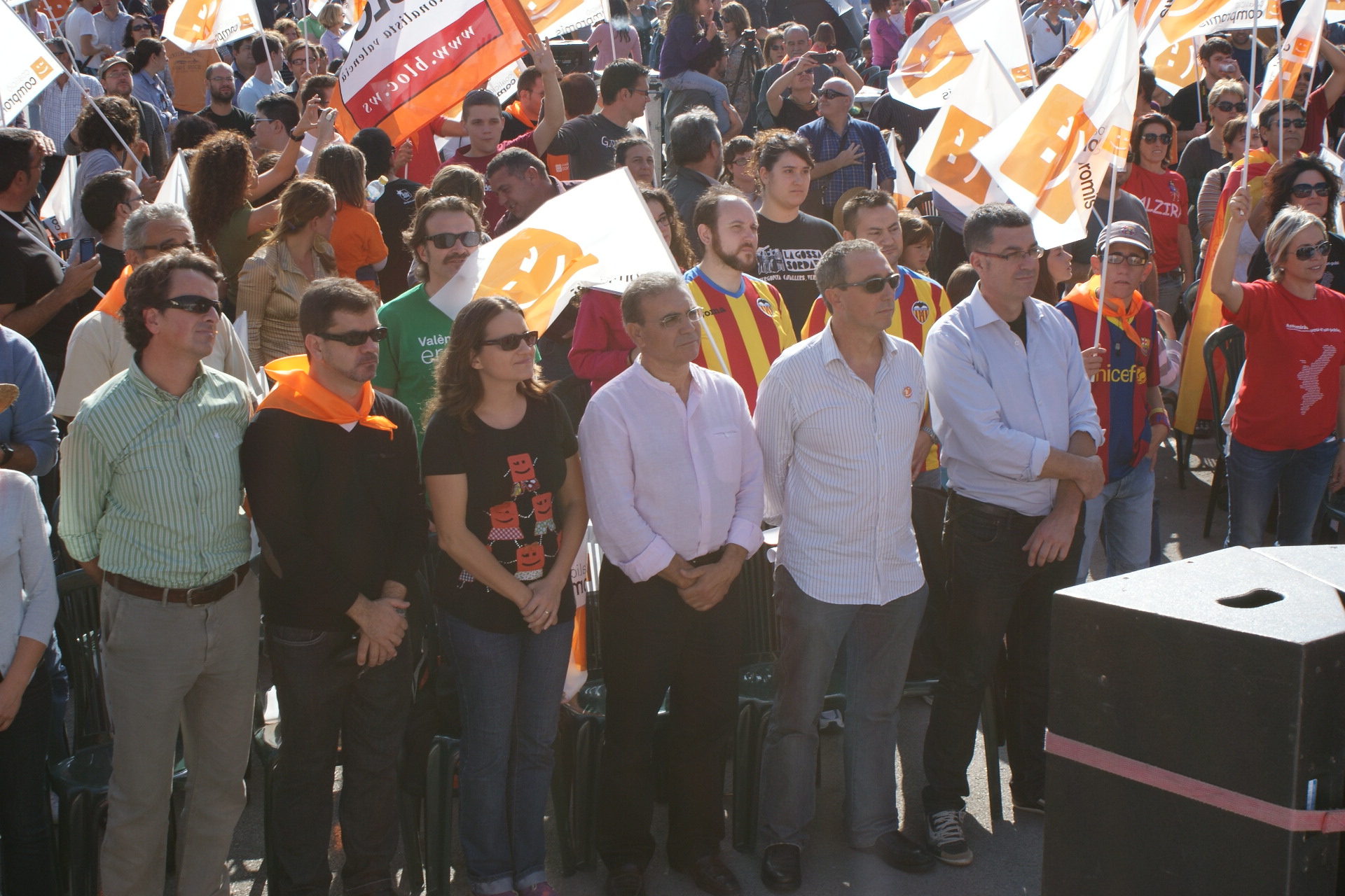 people holding orange and yellow signs on a street