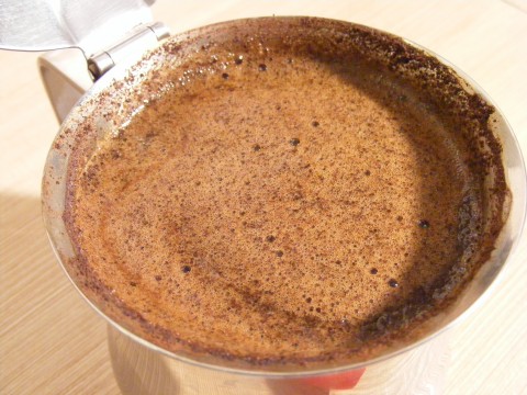 a cup of brown liquid in it next to a spoon