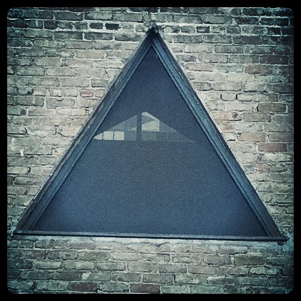 a triangle shaped window on top of a brick building