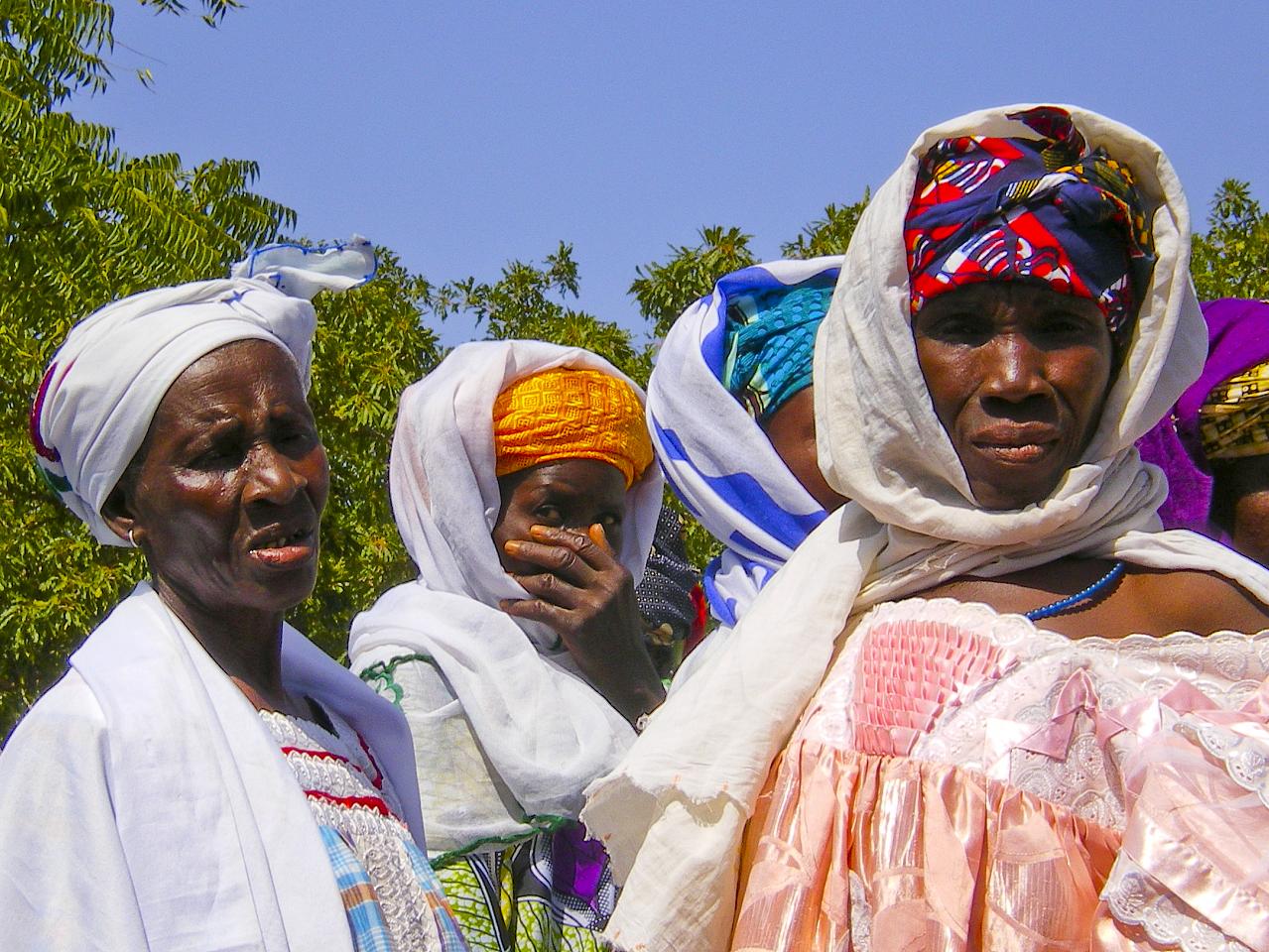 three women in colorful cloths and headscarves stand together