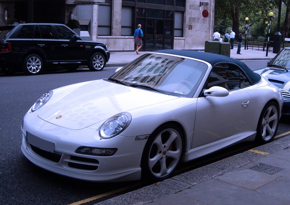 a porsche sports car sits parked in front of two other cars