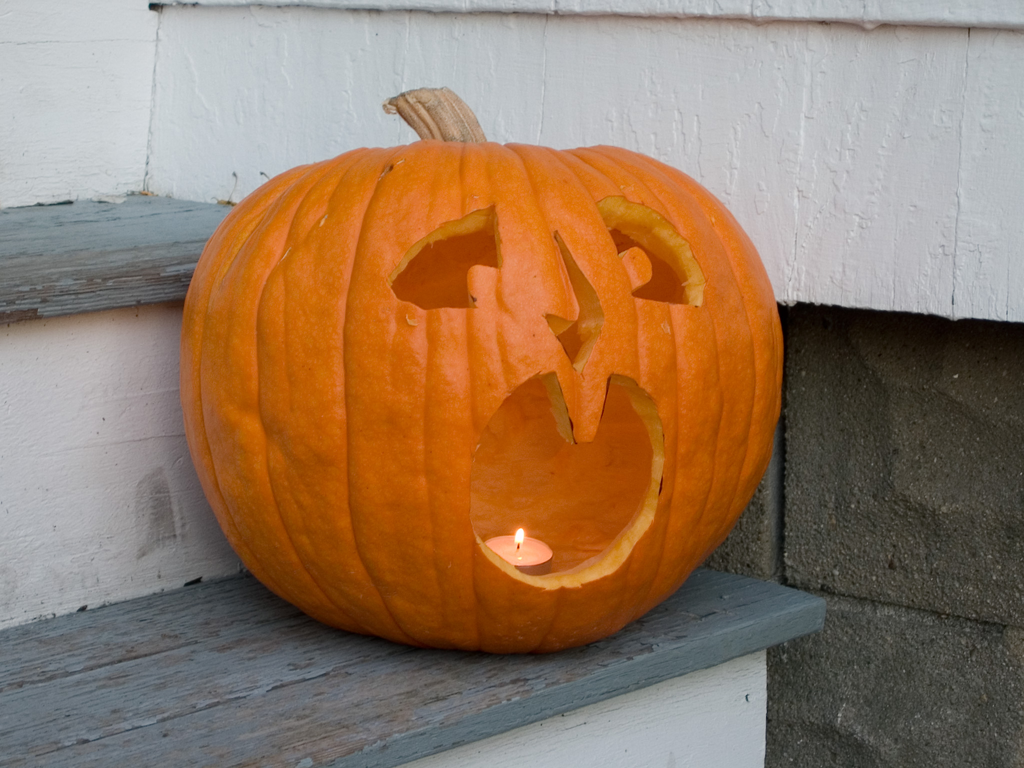 a carved pumpkin on the porch near a house