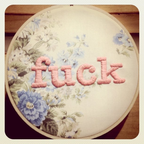 embroideryed pink letters and blue flowers are on a white piece of fabric