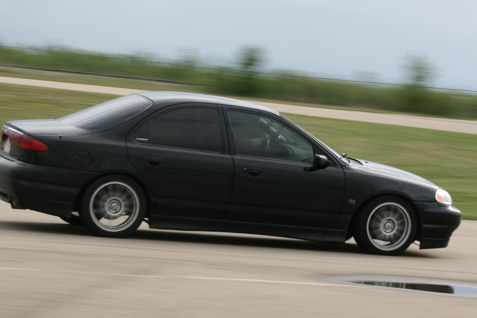 black car driving down a road during the day