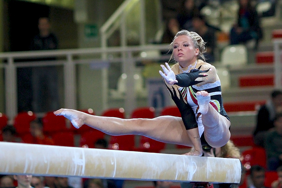 a girl doing the splits while holding onto a bar