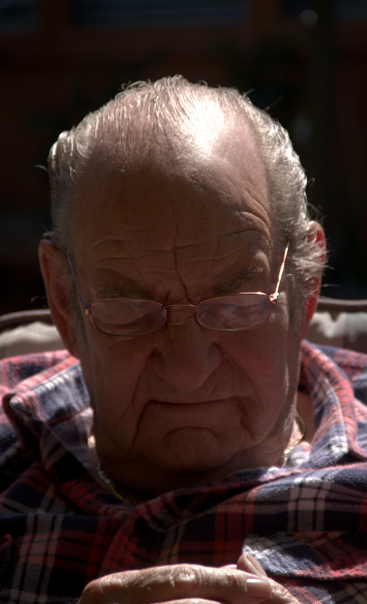 an elderly man with glasses in plaid shirt