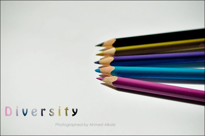 a group of colored pencils sit side by side