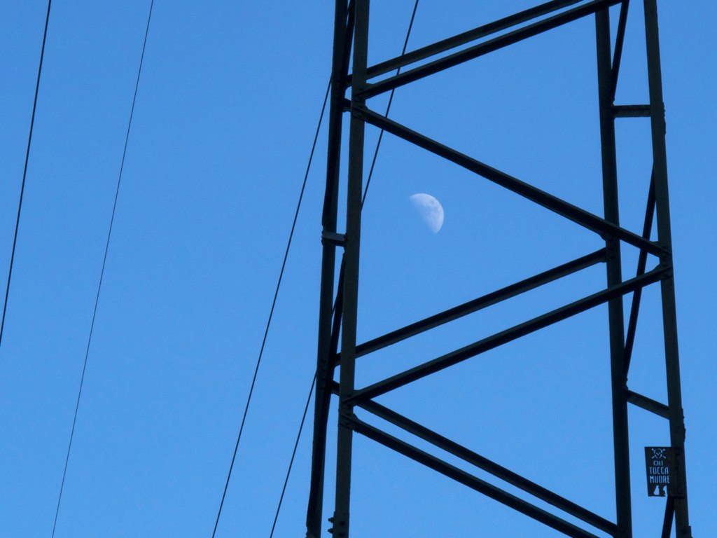 a power tower and the moon in the distance