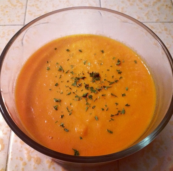 a bowl of carrot soup sits on a counter