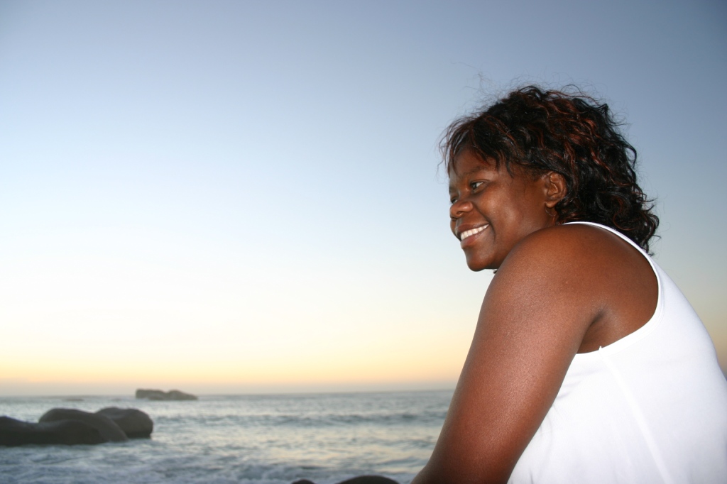 a woman in white top and rocks near water