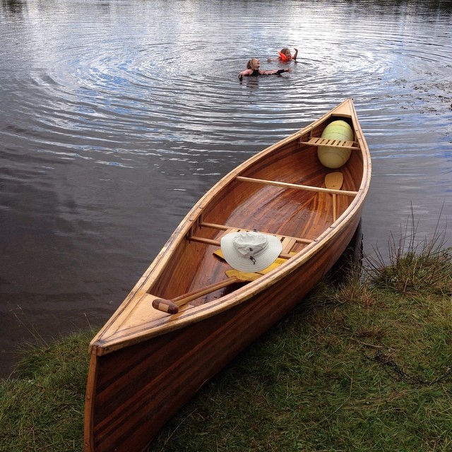 a wooden boat tied to the side of a lake