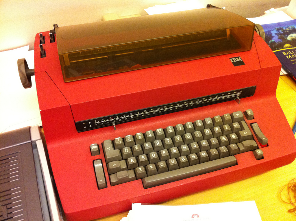 an old red typewriter sitting on top of a table