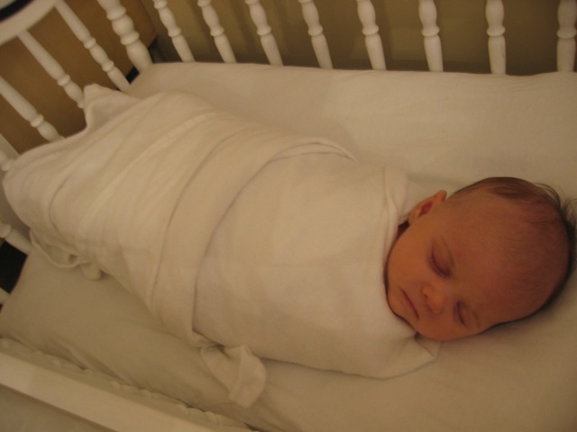 a small baby sleeping in a crib made of white wood