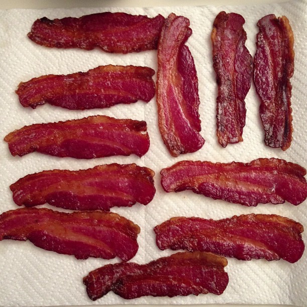 bacon pieces on a white napkin sit in a row