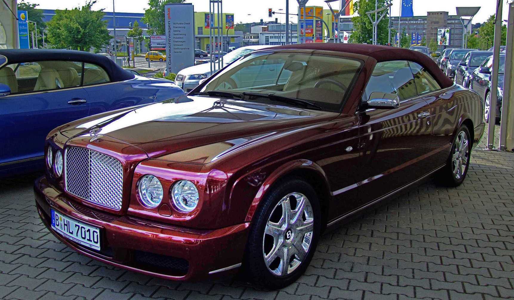 a large red car parked on a cobblestone street