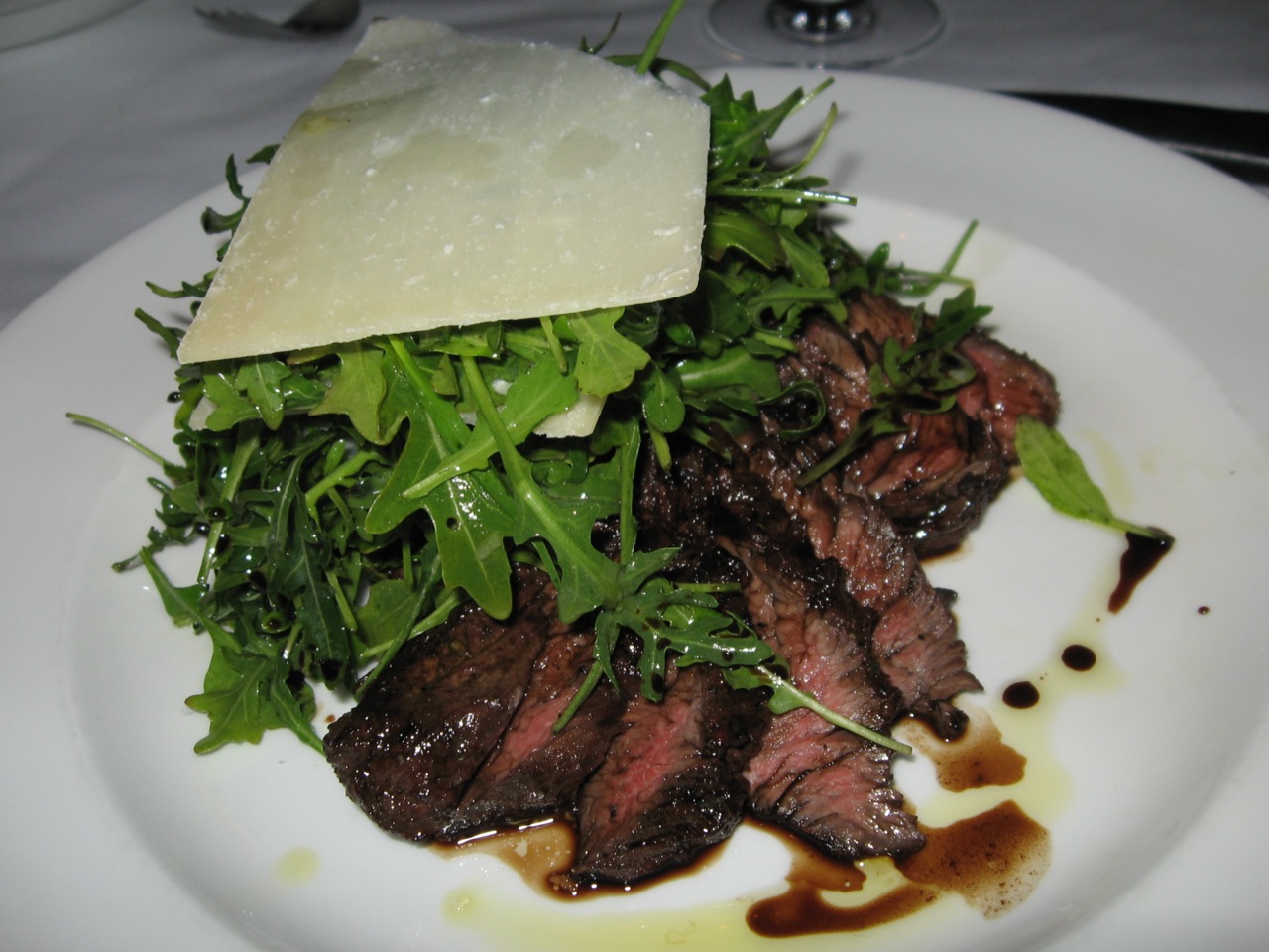 a steak entree and some parmesan cheese on a plate