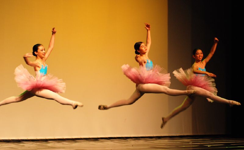 three ballet dancers performing a dance position with one dancing