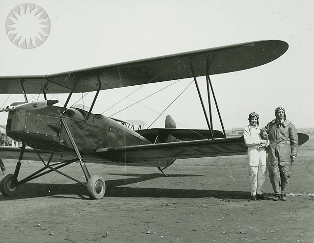an old po with a man and a woman standing by a plane