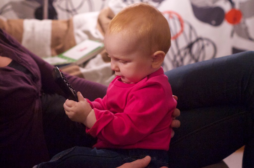 a small child sitting on someone's lap looking at a phone