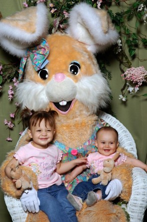 two children pose with a bunny on a chair