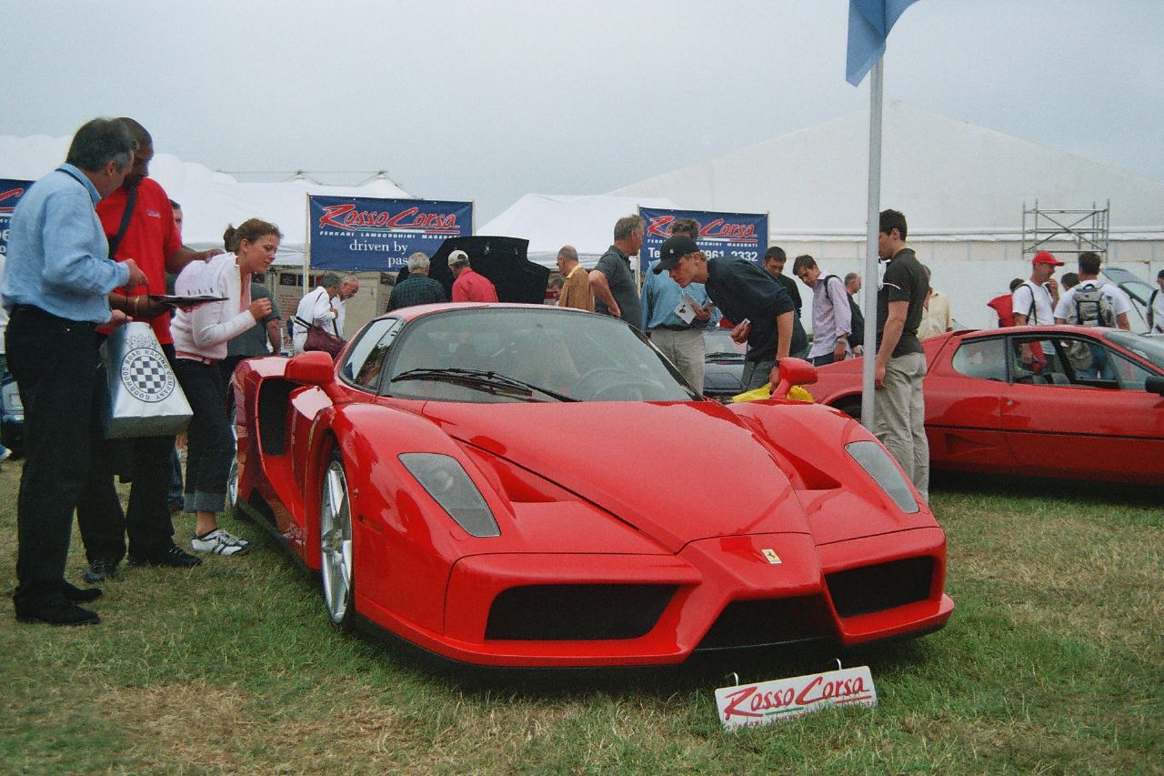 many people are gathered around a sports car