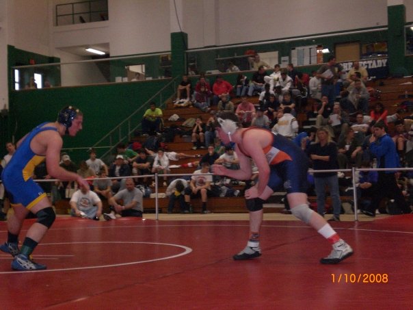two wrestlers in blue and yellow standing on the court