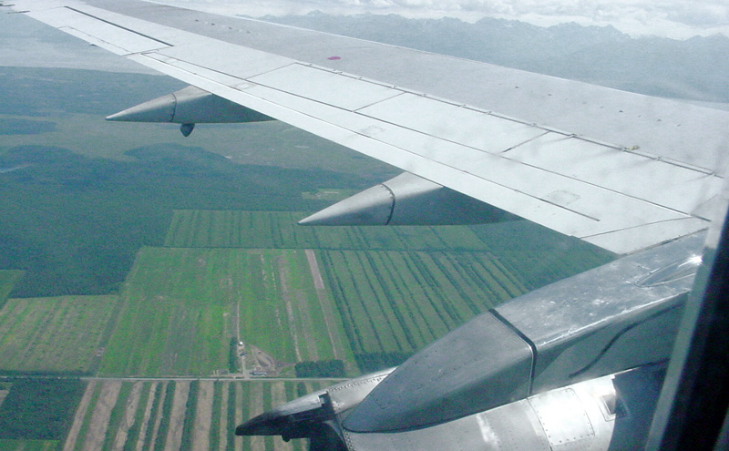 airplane wing view over farm land near water