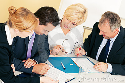 three business people sitting at a table in front of a clipboard
