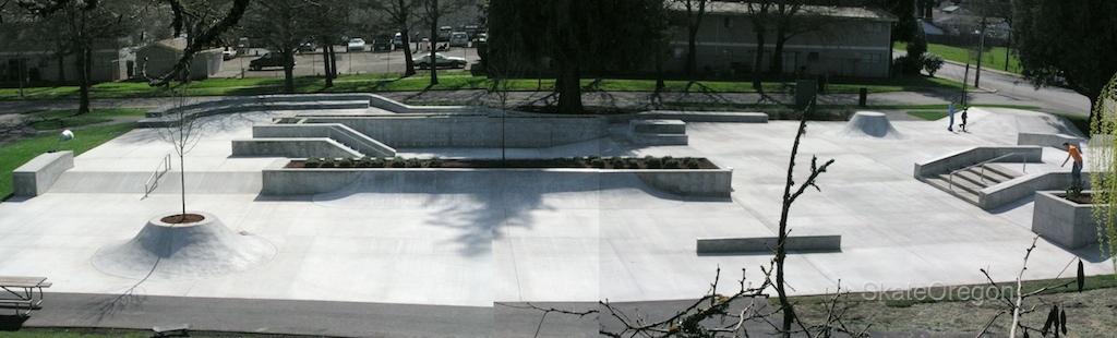 a cement park area with a concrete skateboard ramp