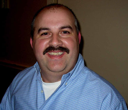 a man with a mustache smiling at the camera