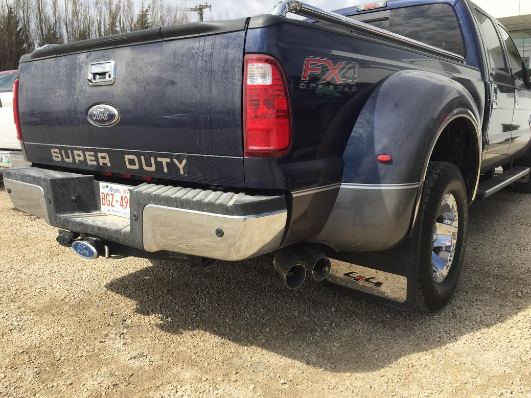 the rear end of a blue pick up truck parked on the side of a road