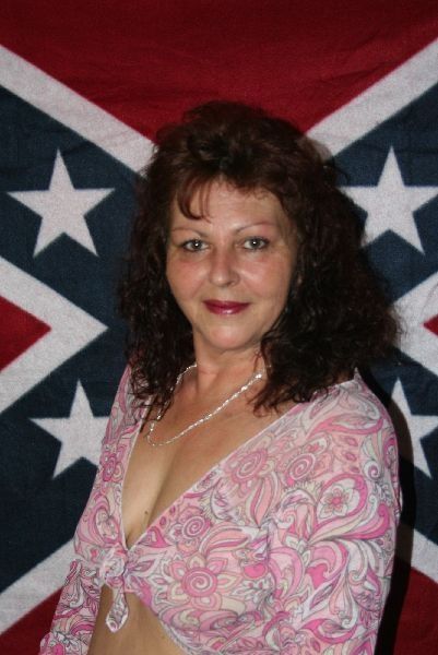 a woman in pink shirt standing next to an american flag
