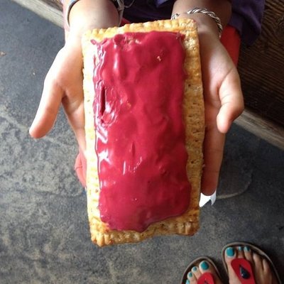 a person holding up some kind of bread with red frosting