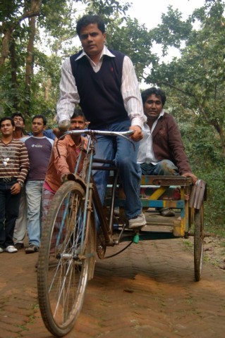 a man on a bicycle with another boy riding in the background