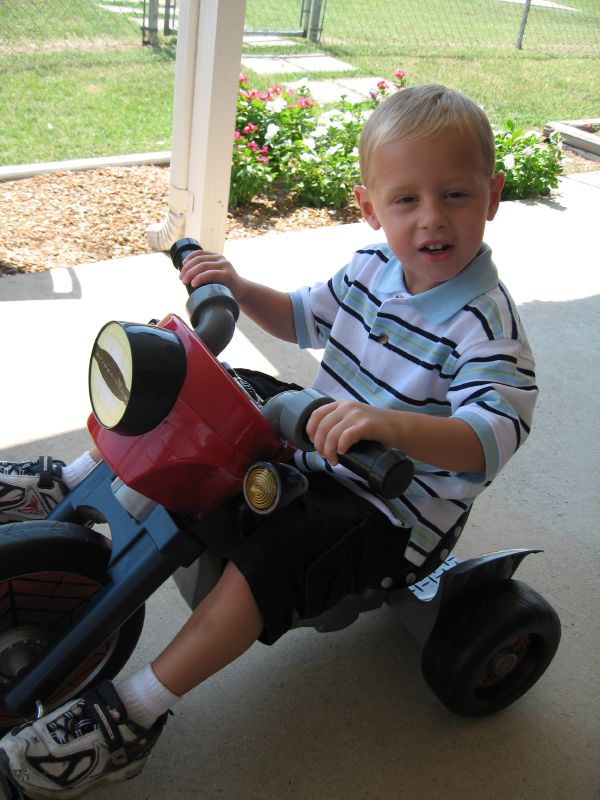 a boy with a helmet on riding a tricycle