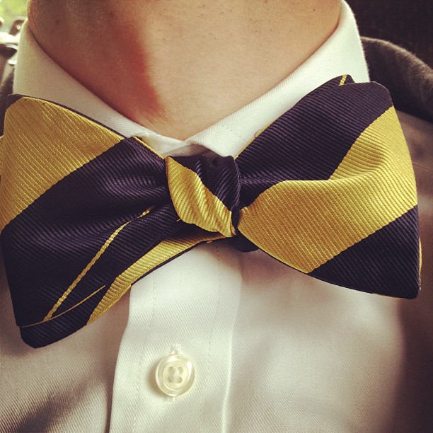 the man is wearing a yellow, black and white bow tie