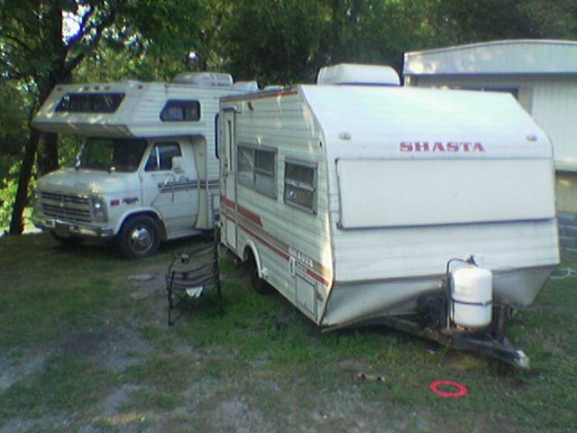 an rv, camper, truck and camp trailer in a grassy area