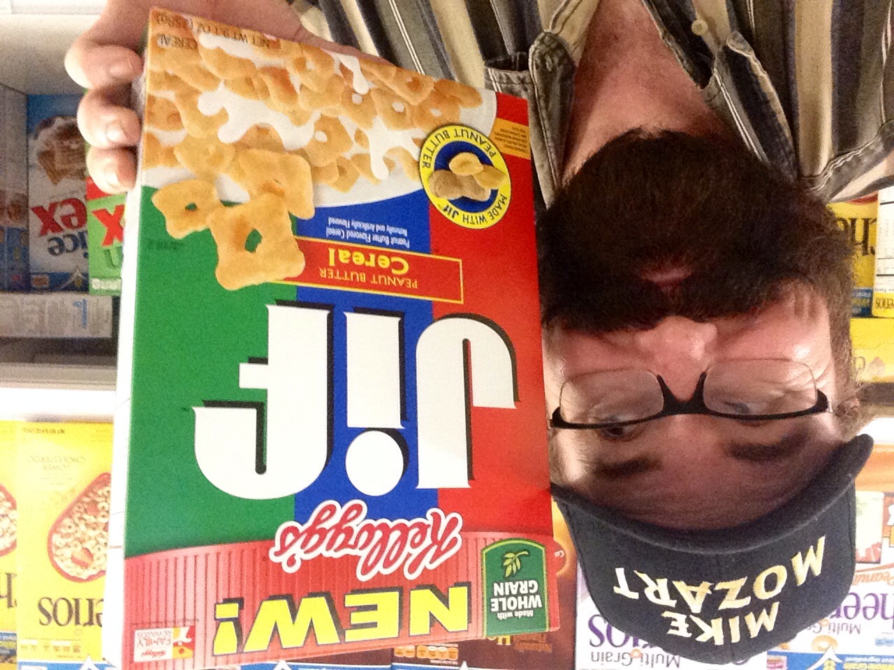 a man holds up a box of cereal and wears glasses