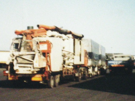 two trucks are driving down the road carrying cargo