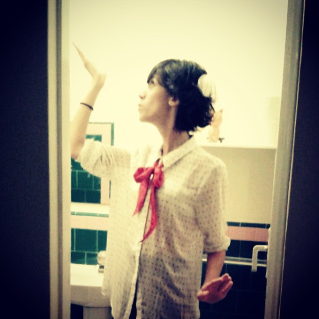 a woman standing in front of a mirror and pointing to the sky