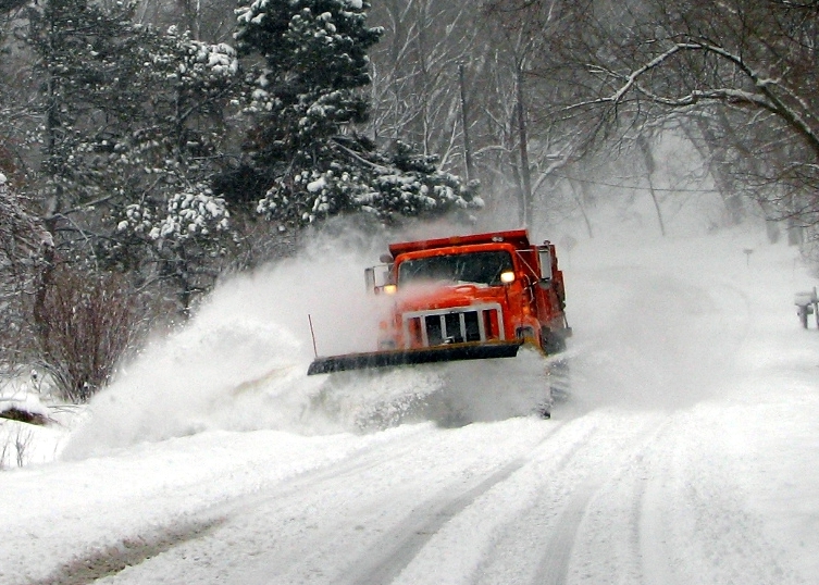 a snow plow moving through the snow on a road