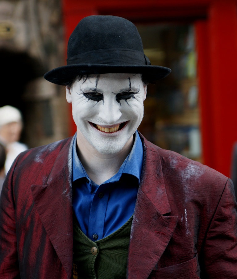 man dressed up as a joker wearing a top hat