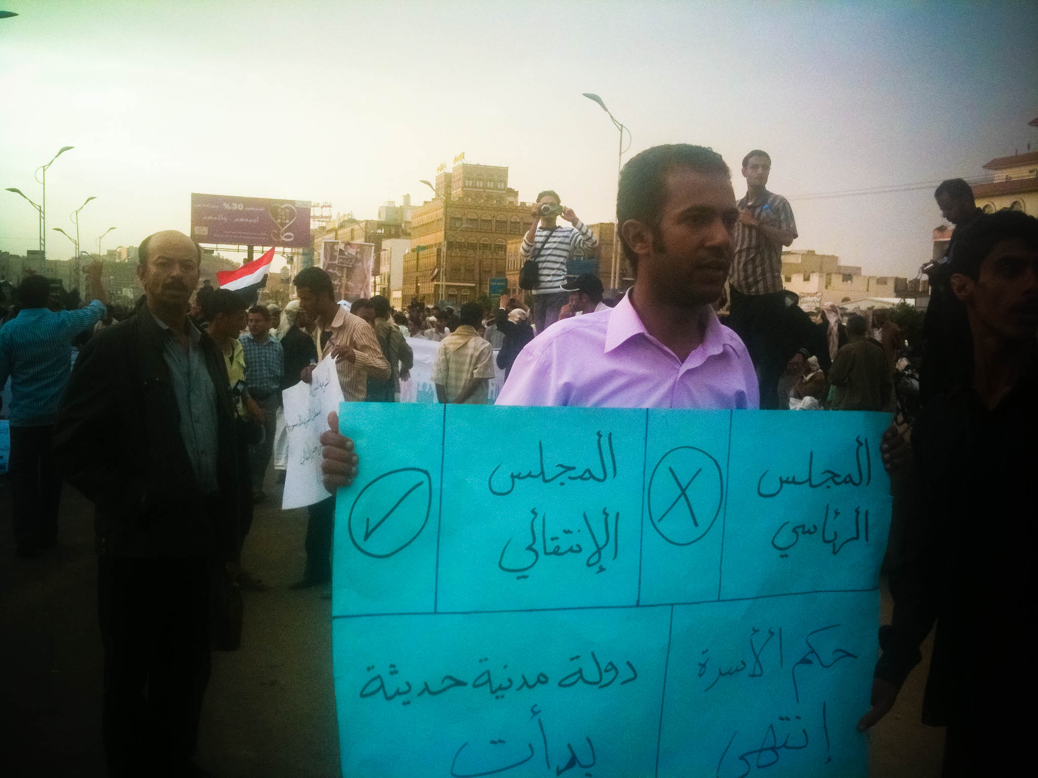 a man holding a sign near other people on the street