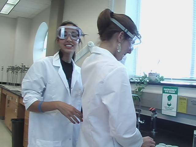 two women are standing next to each other in lab coats