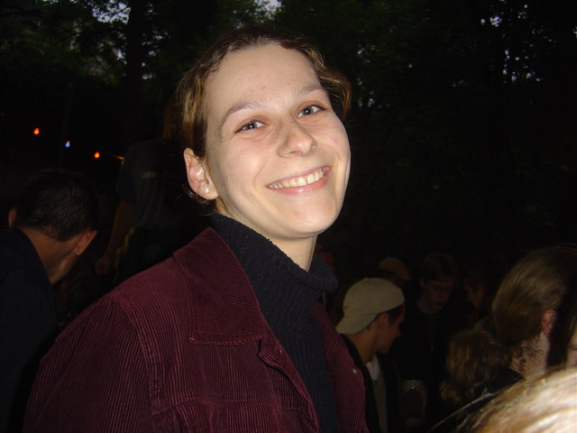 a smiling young lady wearing a maroon jacket and black top
