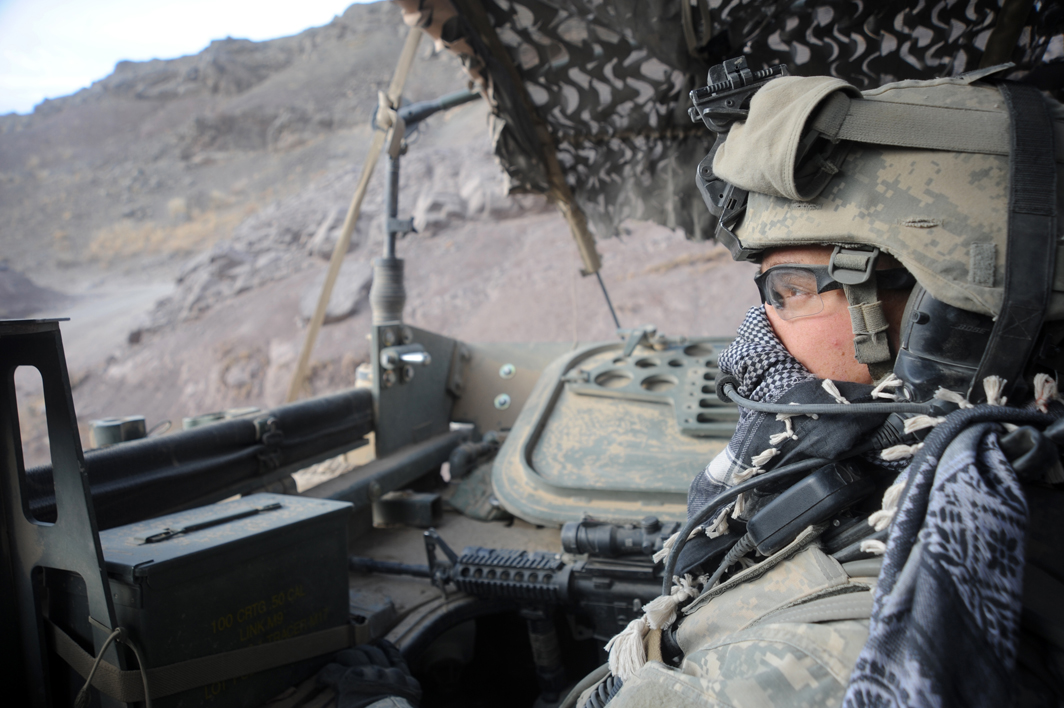 two people wearing glasses, sitting in an army vehicle