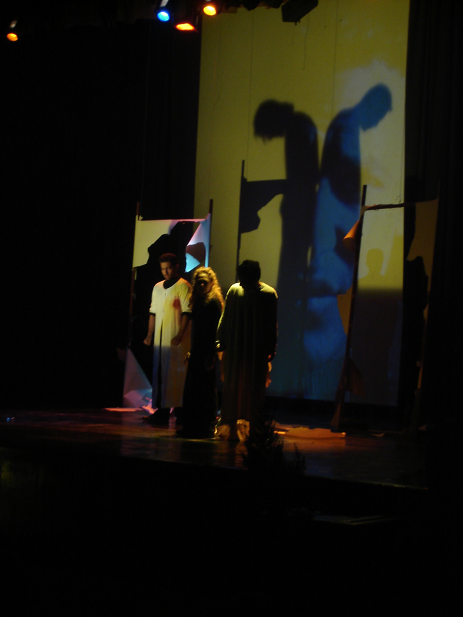 several people are standing on stage with the shadow of a person
