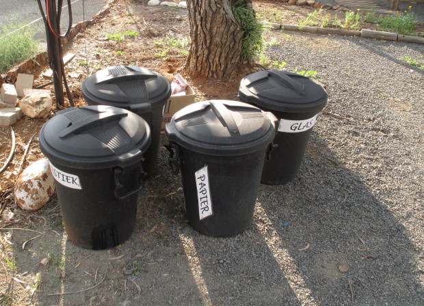 three trash cans sitting next to a tree