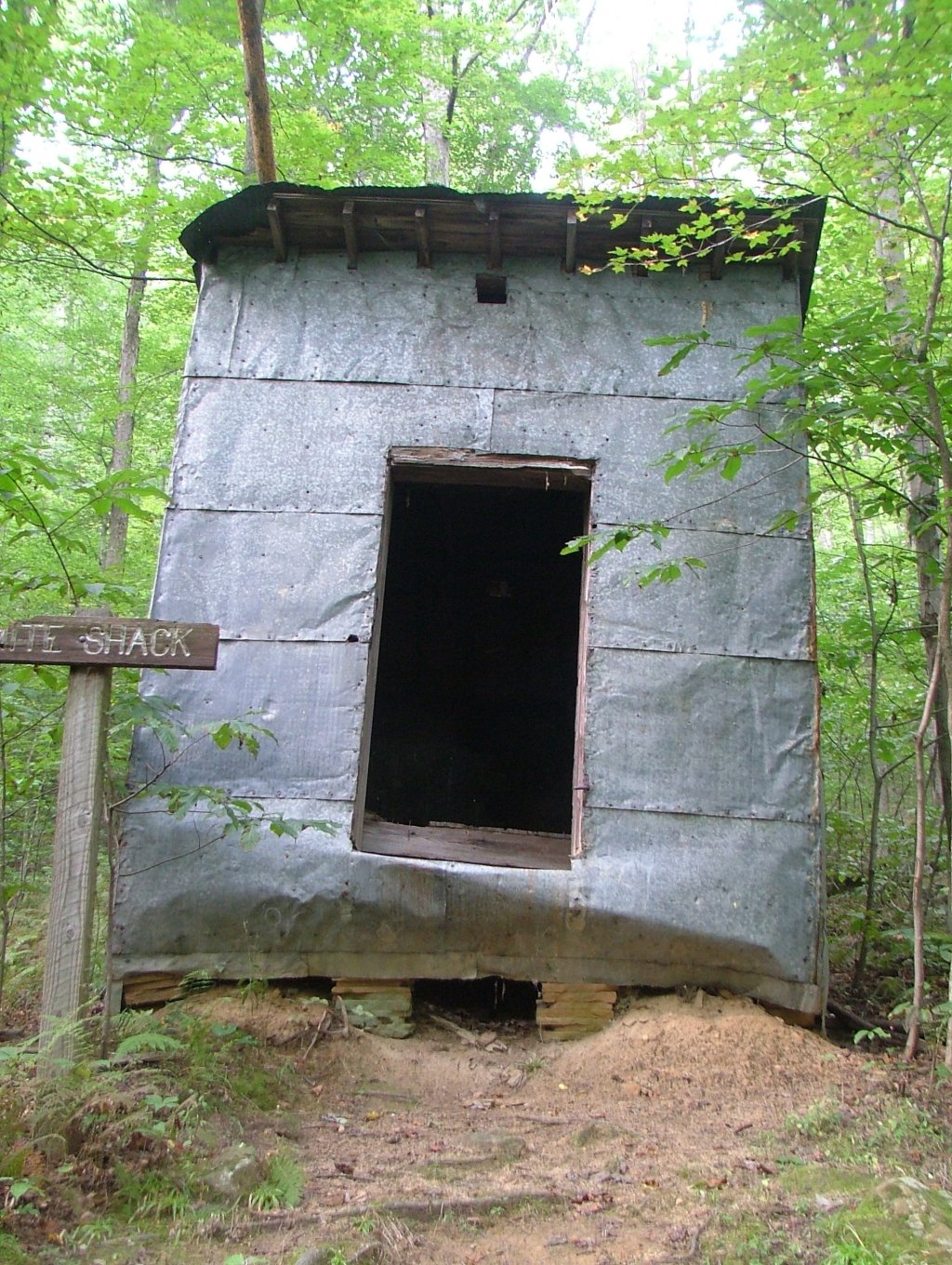 a house in the woods near a cross with an open door