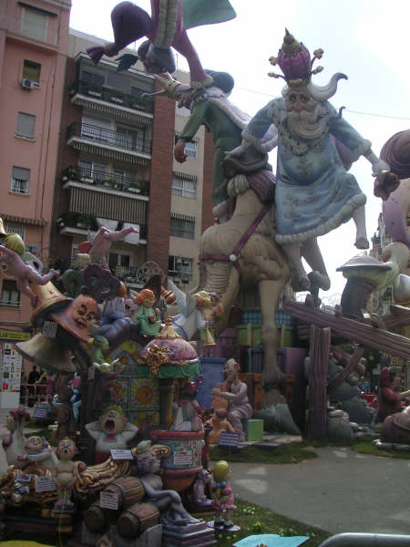 a parade featuring an elaborately decorated statue and a tall brick building